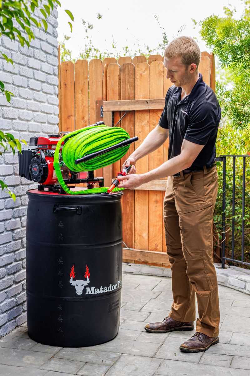 Matador Fire technician with the hose beside a 50 gallon retardant barrel and pump
